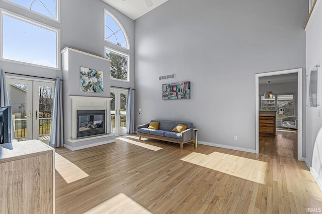 unfurnished living room with baseboards, visible vents, wood finished floors, and a glass covered fireplace