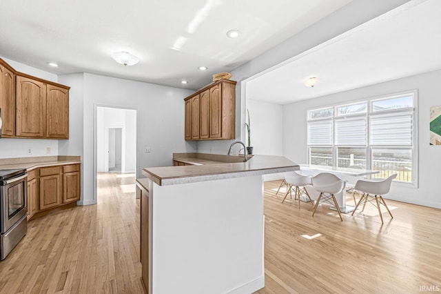 kitchen with light wood finished floors, recessed lighting, a sink, stainless steel range with electric stovetop, and a peninsula