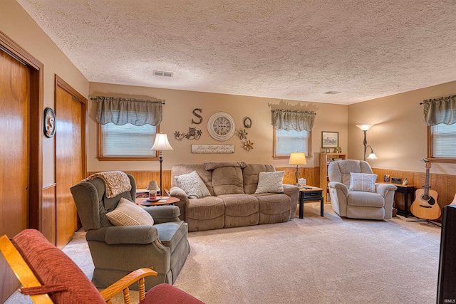 living area with a healthy amount of sunlight, visible vents, and wainscoting