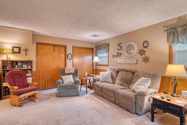 living area featuring carpet, visible vents, and a textured ceiling