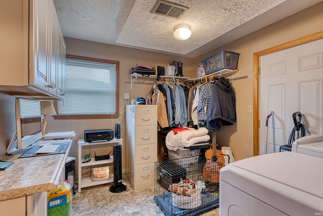 laundry area with cabinet space, washing machine and clothes dryer, visible vents, and a textured ceiling