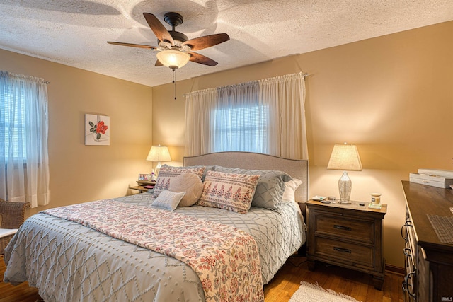 bedroom with a textured ceiling, a ceiling fan, and wood finished floors