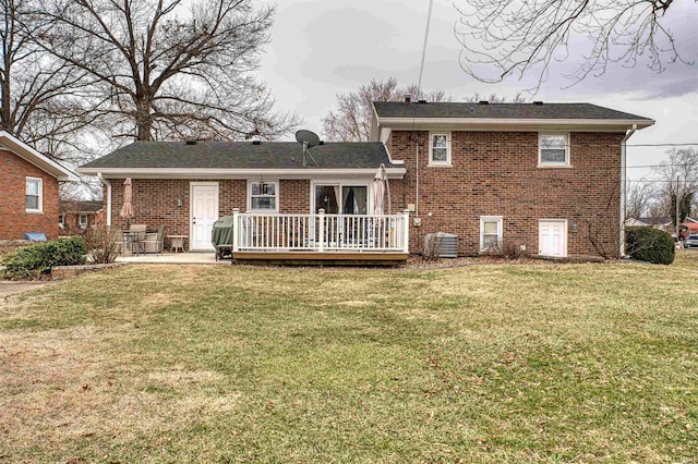 rear view of property with a deck, a yard, brick siding, and a patio area