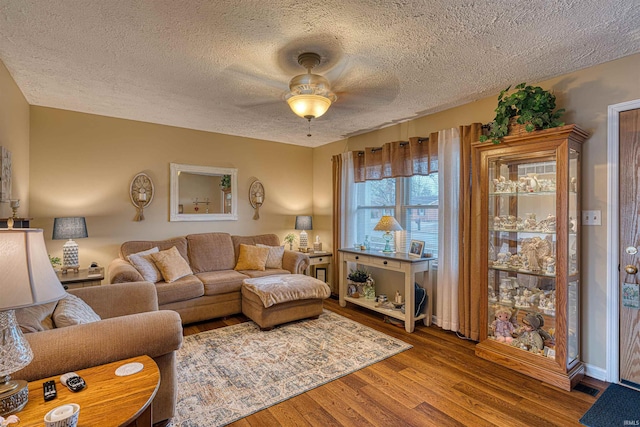 living room featuring ceiling fan, a textured ceiling, and wood finished floors