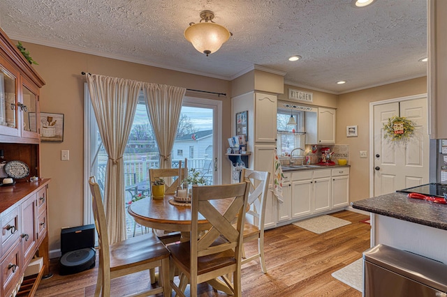 dining space featuring light wood-style flooring, a textured ceiling, crown molding, and recessed lighting