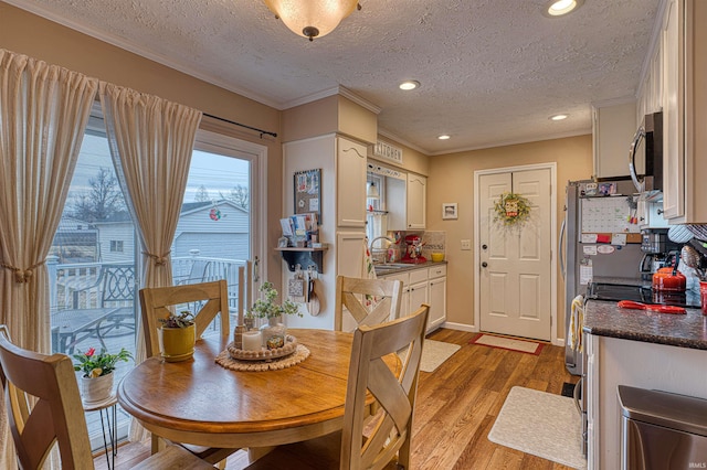 dining area featuring a textured ceiling, recessed lighting, baseboards, ornamental molding, and light wood-type flooring