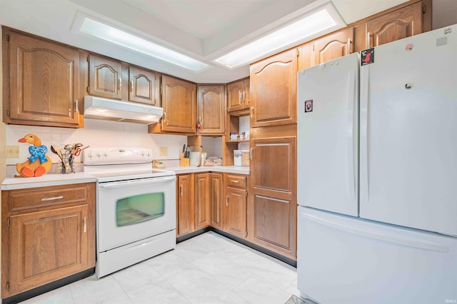 kitchen featuring white appliances, under cabinet range hood, light countertops, and decorative backsplash