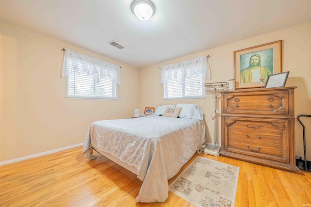 bedroom with light wood-style floors, baseboards, and visible vents