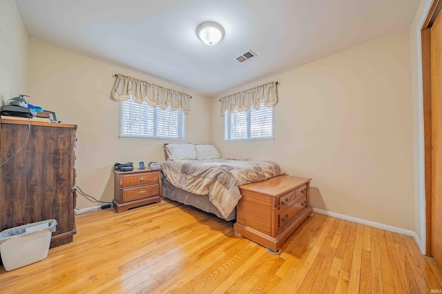 bedroom with light wood-style floors, visible vents, and baseboards