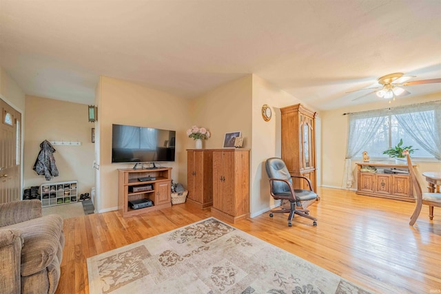 living room with a ceiling fan, baseboards, and wood finished floors