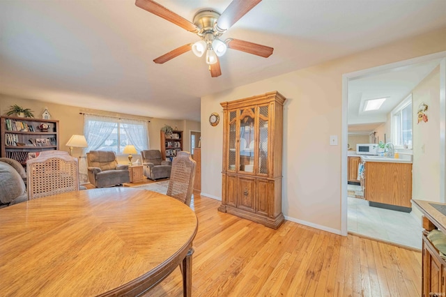 dining area featuring ceiling fan, light wood finished floors, and baseboards