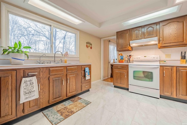 kitchen featuring white electric range, brown cabinetry, a sink, and under cabinet range hood