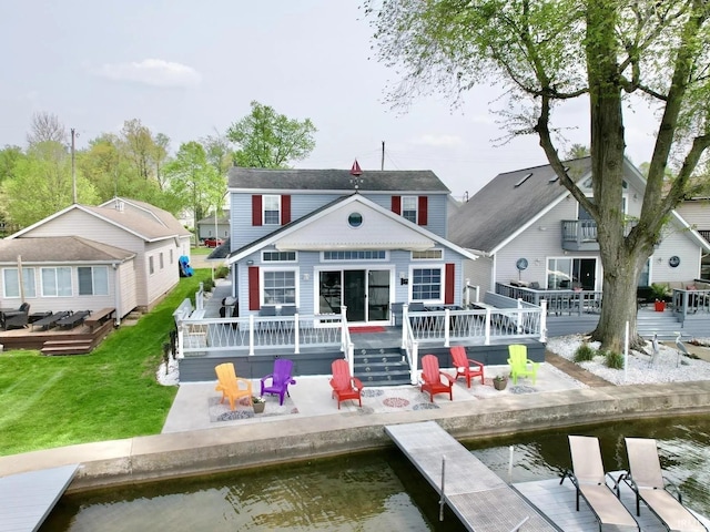 rear view of house featuring a patio area, a lawn, and a deck with water view