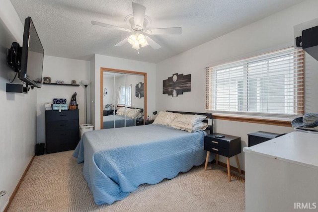 bedroom featuring a textured ceiling, a closet, a ceiling fan, and light colored carpet