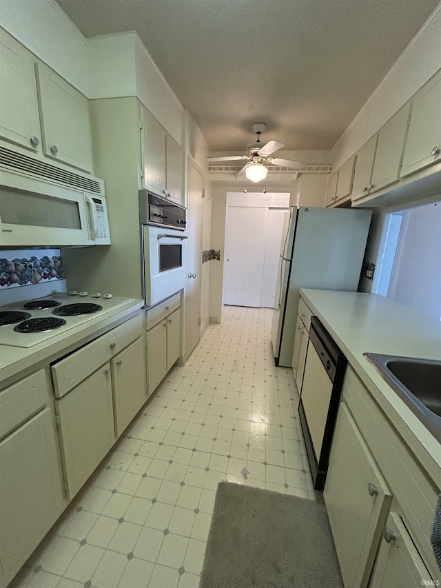 kitchen featuring white appliances, ceiling fan, light countertops, light floors, and a sink