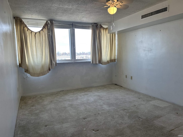 carpeted empty room with a ceiling fan, visible vents, and a textured ceiling