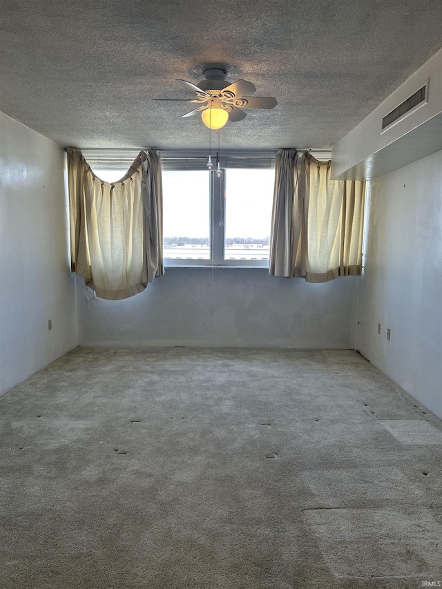 carpeted empty room featuring visible vents and a textured ceiling