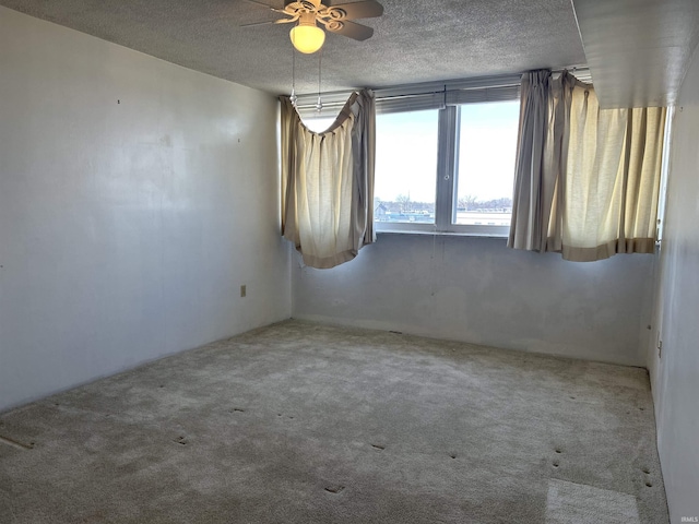 carpeted empty room featuring a textured ceiling and a ceiling fan