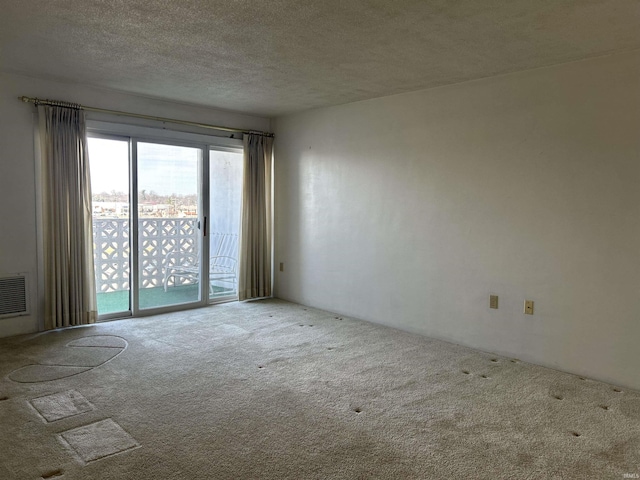 spare room featuring a textured ceiling, visible vents, and carpet flooring