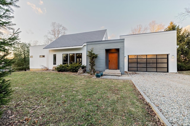 contemporary house with a garage, gravel driveway, and a front yard