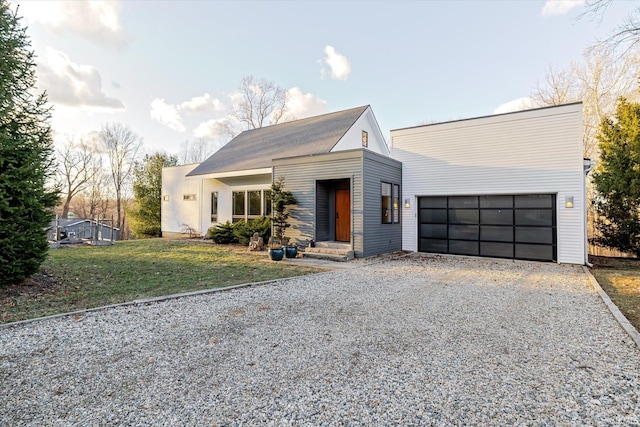 view of front facade with an attached garage, a front lawn, and gravel driveway