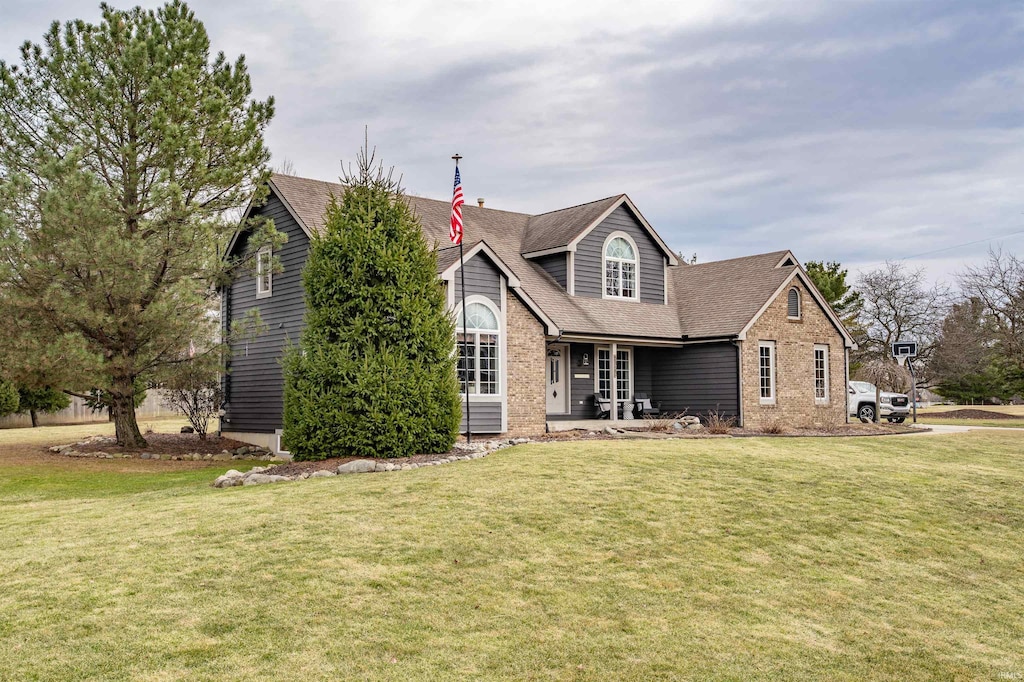 traditional home with brick siding, a shingled roof, and a front yard