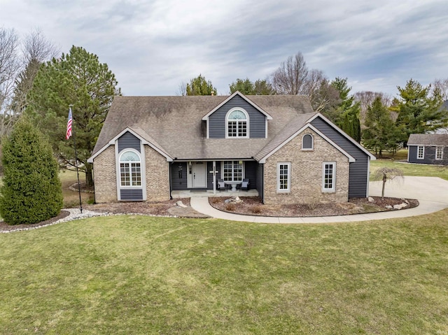 view of front of house with a front lawn, roof with shingles, a porch, and brick siding