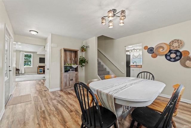 dining space with light wood finished floors, stairway, and baseboards