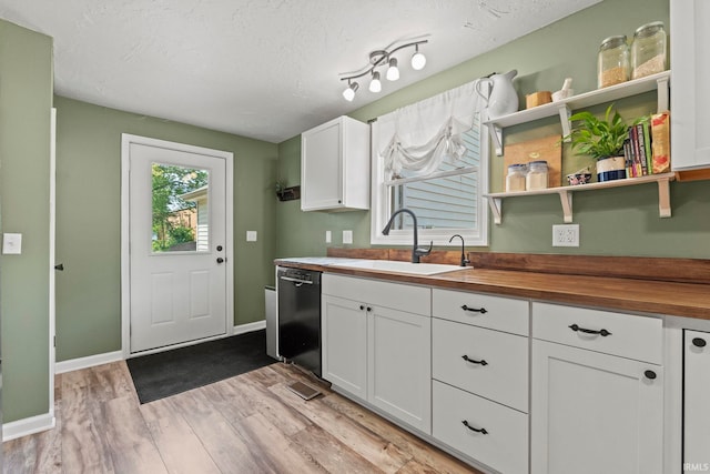 kitchen featuring butcher block countertops, a sink, white cabinetry, light wood-type flooring, and dishwasher