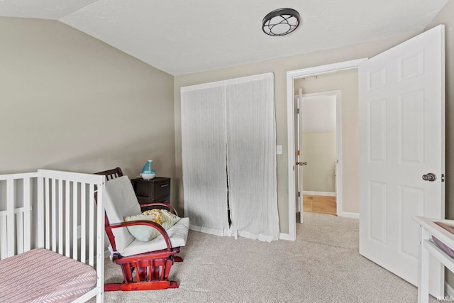 carpeted bedroom with vaulted ceiling, a closet, and baseboards