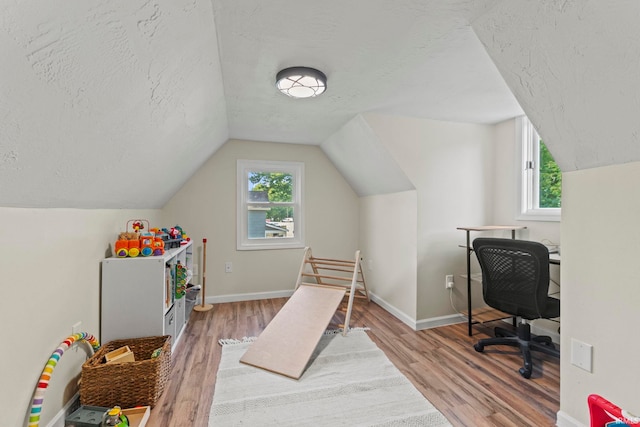 game room featuring baseboards, vaulted ceiling, a textured ceiling, and wood finished floors