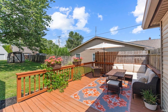 wooden deck with an outbuilding, a fenced backyard, an outdoor living space, a lawn, and a storage unit