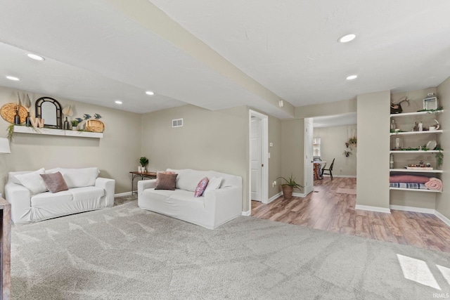 living room featuring visible vents, baseboards, wood finished floors, and recessed lighting