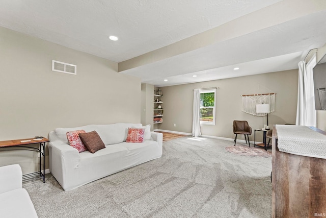 living room with a textured ceiling, recessed lighting, carpet flooring, visible vents, and baseboards