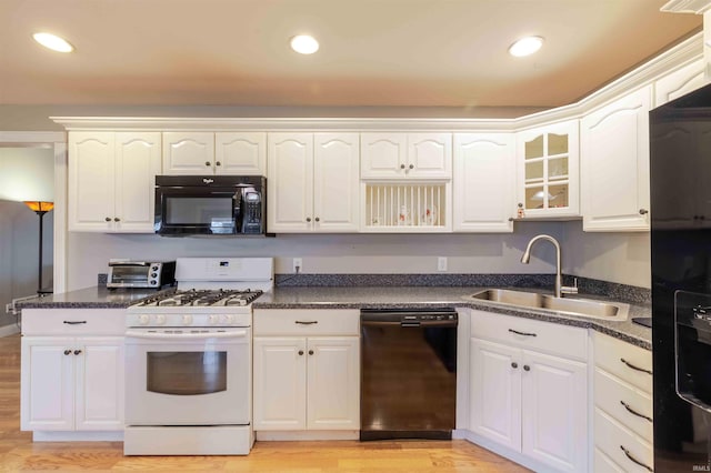 kitchen with dark countertops, light wood-type flooring, black appliances, a sink, and recessed lighting