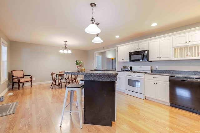 kitchen featuring a breakfast bar, white cabinets, and black appliances