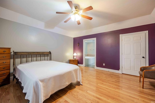 bedroom with light wood-type flooring, ceiling fan, baseboards, and connected bathroom