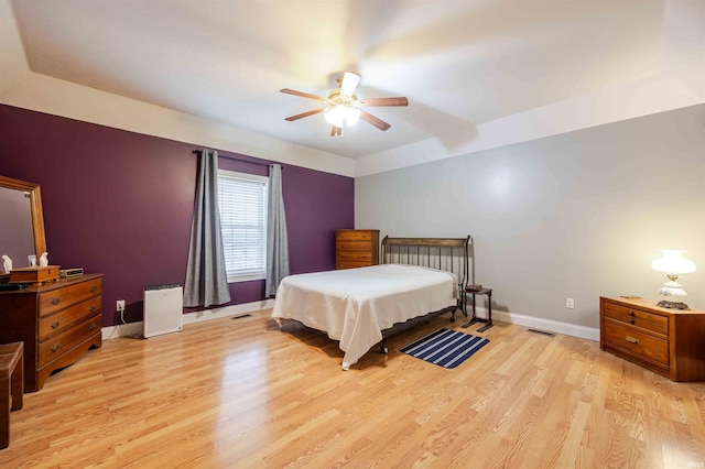 bedroom featuring ceiling fan, light wood finished floors, visible vents, and baseboards