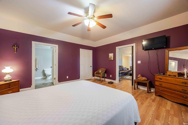 bedroom with baseboards, ceiling fan, light wood finished floors, and ensuite bathroom