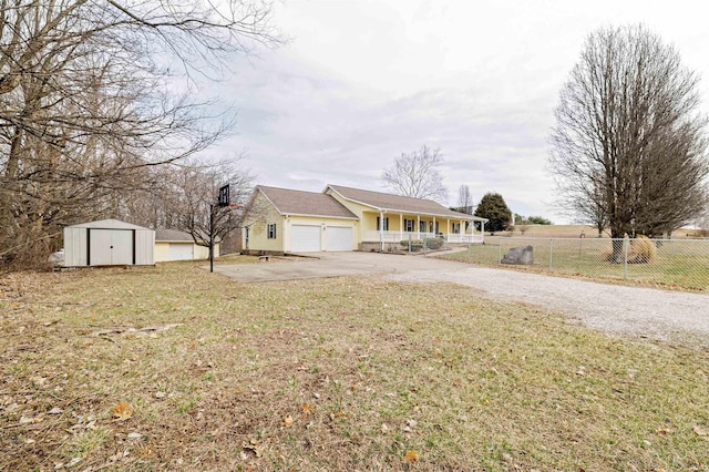 view of front of property featuring driveway, a storage unit, fence, a porch, and a front yard