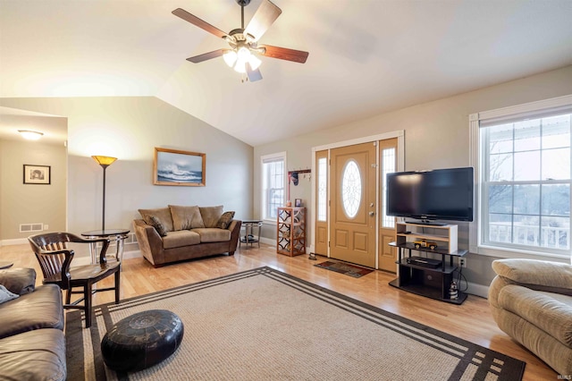 living room with light wood-style floors, a healthy amount of sunlight, visible vents, and vaulted ceiling