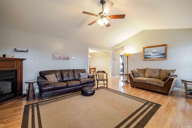 living room featuring a fireplace, lofted ceiling, light wood-style floors, a ceiling fan, and baseboards