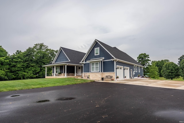 view of front of home with a porch, stone siding, driveway, and a front lawn