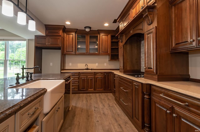 kitchen with hanging light fixtures, black electric stovetop, a sink, and wood finished floors