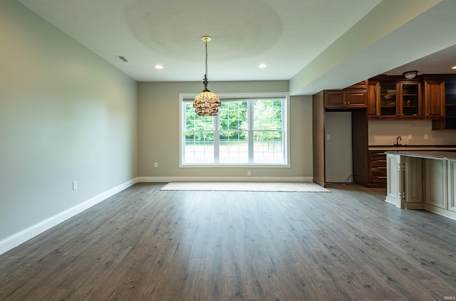 interior space featuring glass insert cabinets, visible vents, baseboards, and wood finished floors