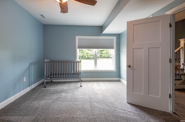 carpeted empty room with ceiling fan, visible vents, and baseboards