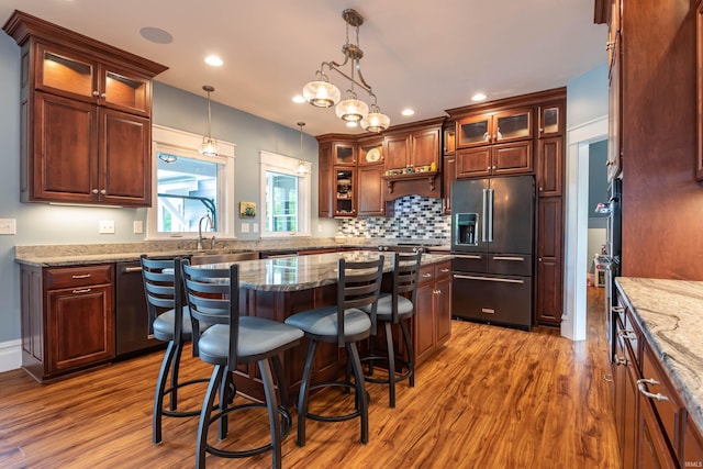 kitchen with appliances with stainless steel finishes, a kitchen bar, wood finished floors, and tasteful backsplash