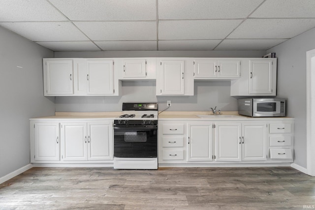 kitchen featuring white cabinets, light wood-style flooring, range with gas stovetop, and a sink