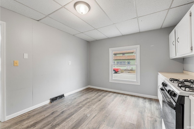 kitchen featuring a paneled ceiling, visible vents, white cabinetry, range with gas stovetop, and light wood-type flooring