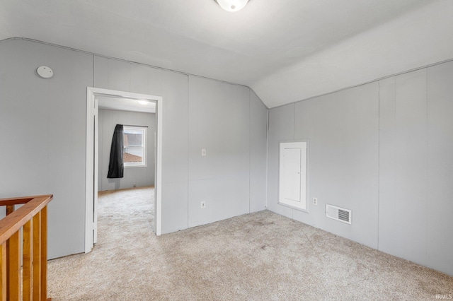 carpeted empty room featuring lofted ceiling and visible vents